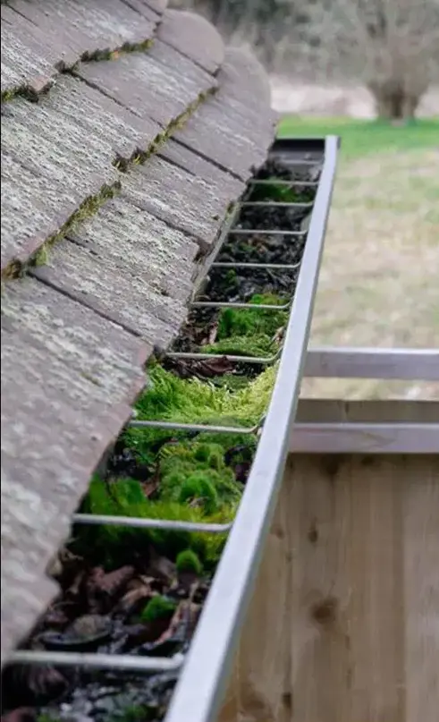 Blocked roof gutters filled with dry leaves and debris posing a fire hazard